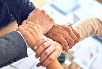 aggregazione aziende, mani che si intrecciano in simbolo di collaborazione